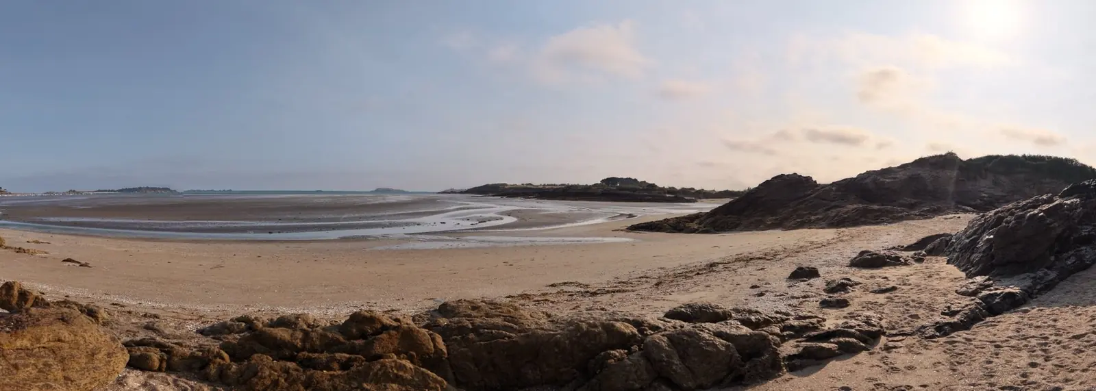 Panorama d'une plage à marée basse entre deux pointes rocheuses